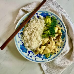 A bowl with jasmine rice, chicken and broccoli with chopsticks placed on the side.